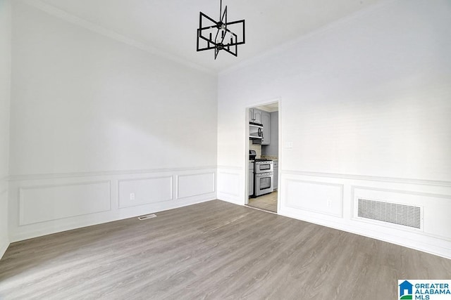 unfurnished room featuring crown molding, an inviting chandelier, and light wood-type flooring