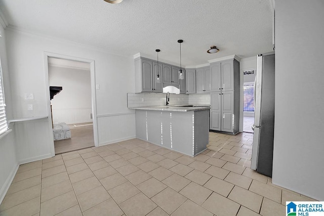 kitchen featuring gray cabinetry, light tile patterned floors, stainless steel fridge, kitchen peninsula, and pendant lighting