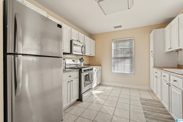 kitchen featuring white cabinetry, appliances with stainless steel finishes, sink, and light tile patterned flooring