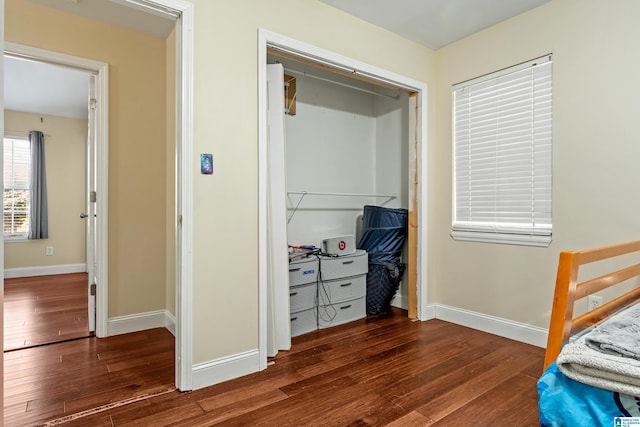 bedroom with dark hardwood / wood-style flooring and a closet