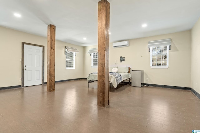 bedroom featuring stainless steel refrigerator, a wall mounted AC, decorative columns, and hardwood / wood-style flooring