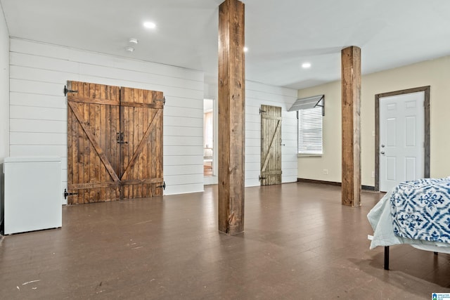 interior space featuring dark wood-type flooring, wooden walls, and decorative columns