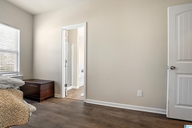 bedroom with ensuite bath and dark hardwood / wood-style floors