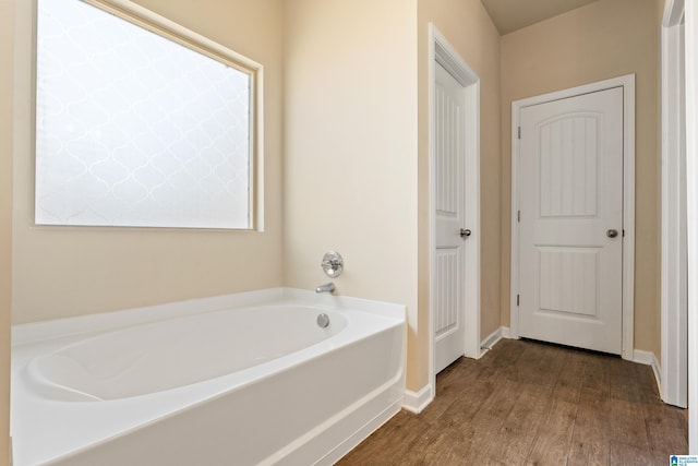 bathroom with a tub to relax in and wood-type flooring
