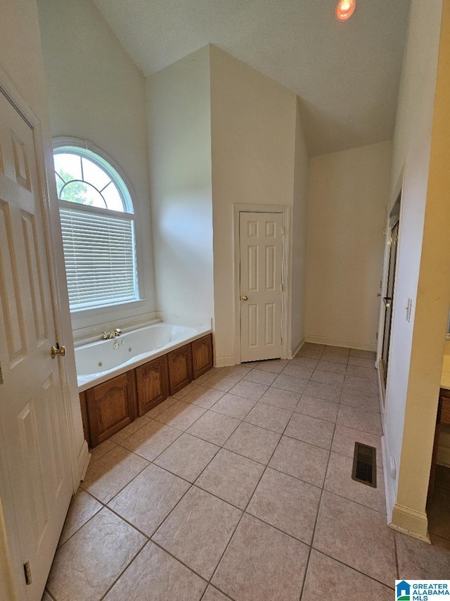 bathroom with a towering ceiling, a bath, and tile patterned flooring