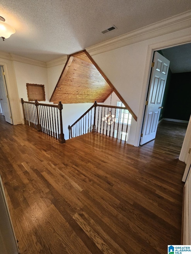 interior space featuring ornamental molding, dark wood-type flooring, and a textured ceiling