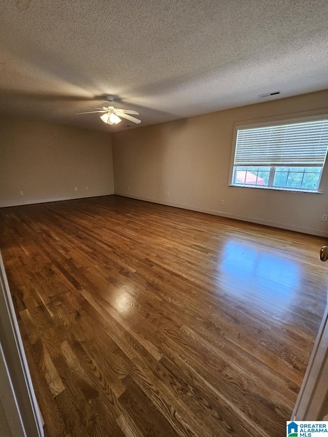 empty room featuring ceiling fan, wood-type flooring, and a textured ceiling