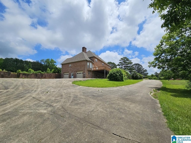 view of property exterior with a wooden deck, a garage, and a yard