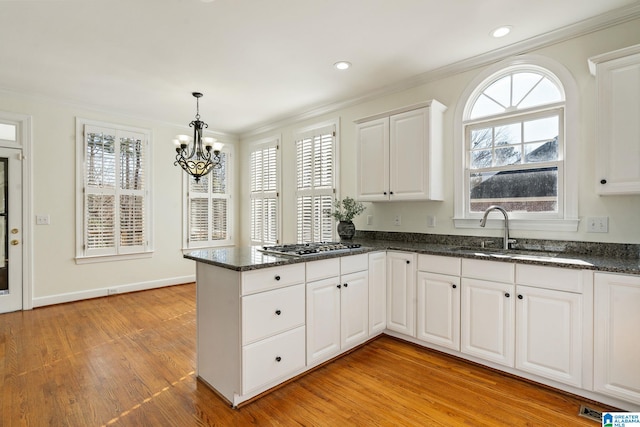 kitchen featuring sink, decorative light fixtures, kitchen peninsula, light hardwood / wood-style floors, and white cabinets