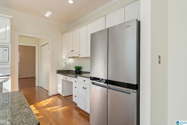 kitchen with light hardwood / wood-style flooring, stainless steel refrigerator, white cabinetry, dark stone countertops, and white microwave