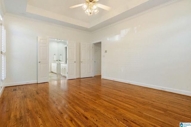 unfurnished room featuring a raised ceiling, crown molding, hardwood / wood-style floors, and ceiling fan