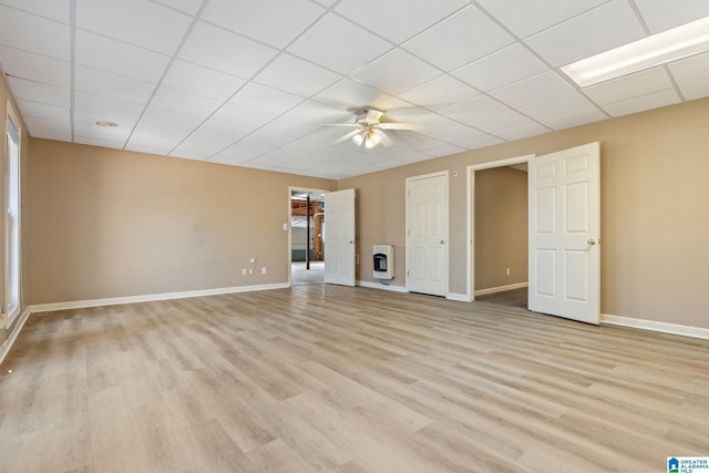 interior space with heating unit, a drop ceiling, ceiling fan, and light hardwood / wood-style flooring