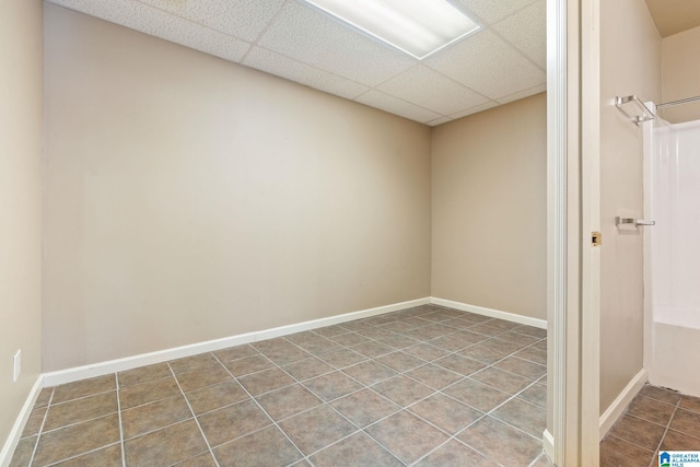 spare room with a paneled ceiling and tile patterned floors