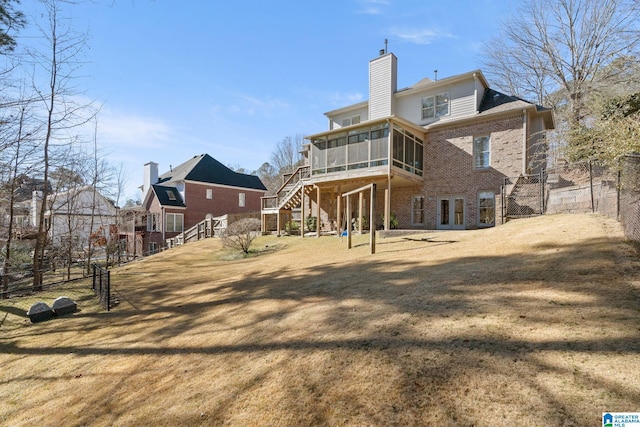 rear view of property featuring a yard and a sunroom