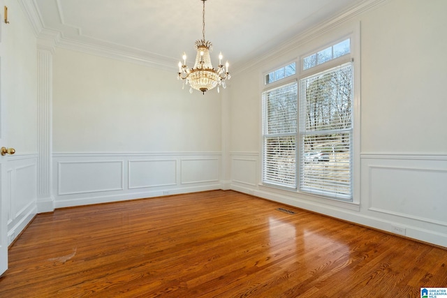 unfurnished room with an inviting chandelier, crown molding, and hardwood / wood-style floors