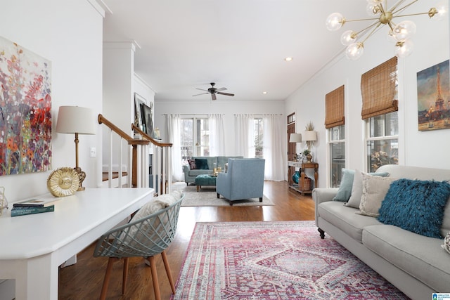 living room with hardwood / wood-style flooring, crown molding, and ceiling fan with notable chandelier