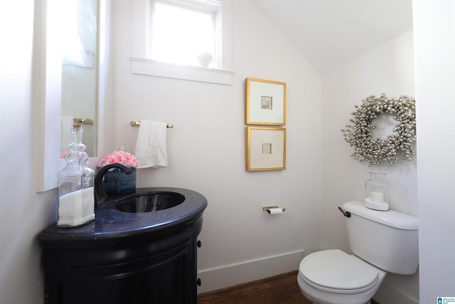 bathroom with vanity, wood-type flooring, vaulted ceiling, and toilet