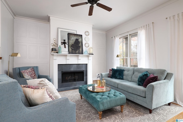 living room featuring a tiled fireplace, crown molding, and ceiling fan