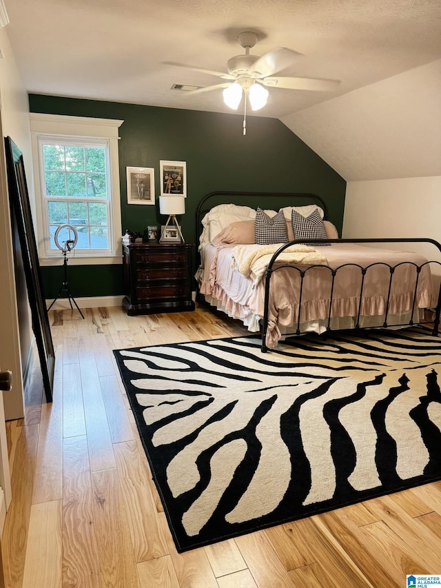 bedroom with vaulted ceiling, light hardwood / wood-style floors, and ceiling fan