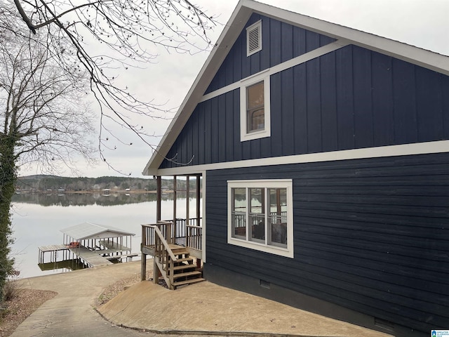 view of property exterior with a water view and a boat dock