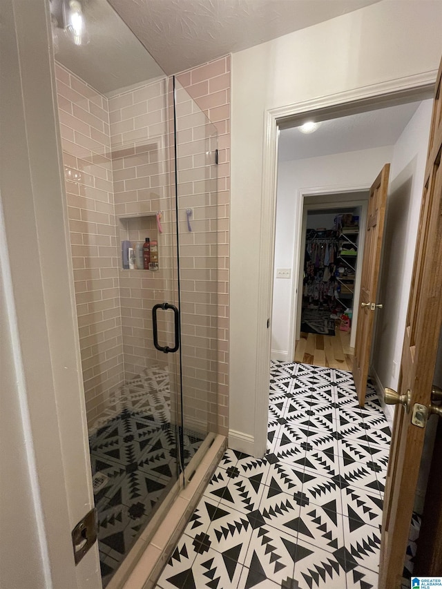 bathroom featuring a shower with shower door and a textured ceiling