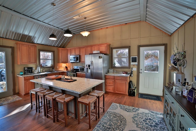 kitchen featuring a kitchen island, appliances with stainless steel finishes, a kitchen bar, hardwood / wood-style flooring, and hanging light fixtures