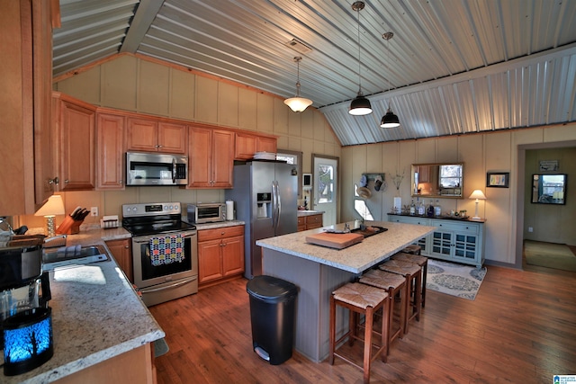 kitchen featuring hanging light fixtures, light stone countertops, appliances with stainless steel finishes, and a center island