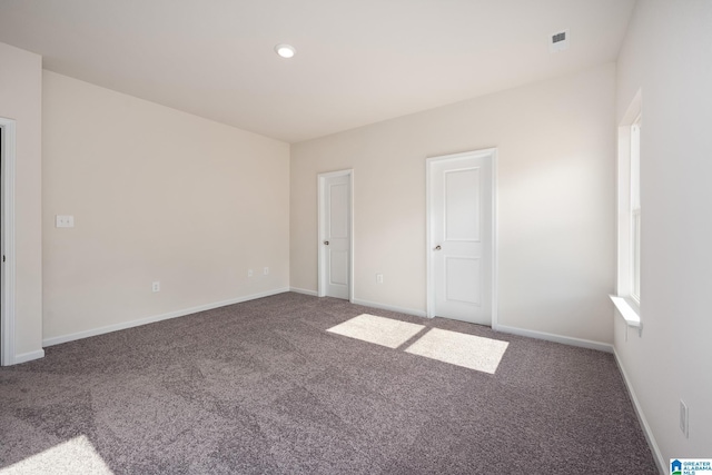 unfurnished room with dark colored carpet