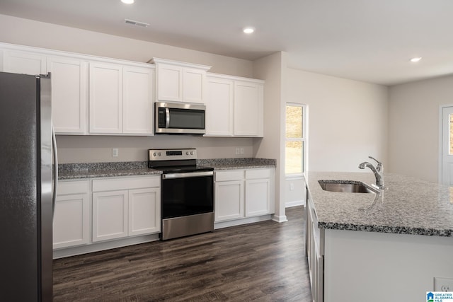 kitchen featuring sink, stainless steel appliances, white cabinets, a center island with sink, and dark hardwood / wood-style flooring