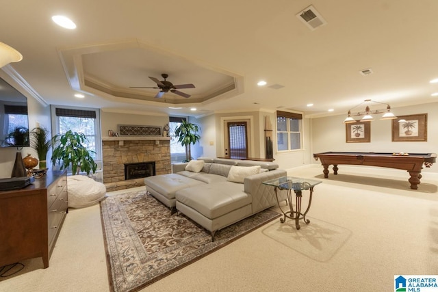 living room featuring crown molding, billiards, carpet, a stone fireplace, and a raised ceiling