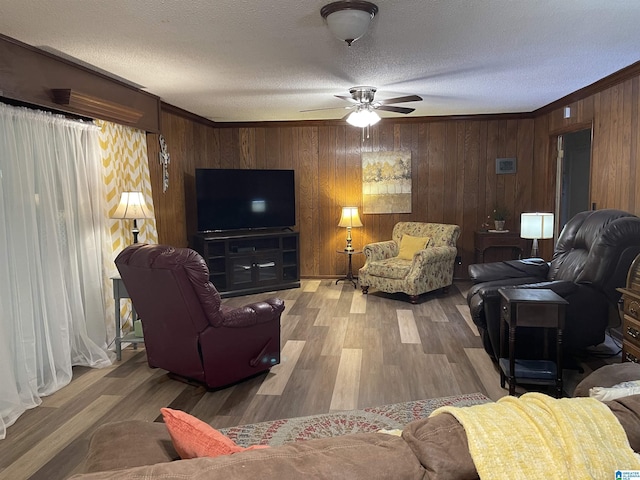 living room featuring hardwood / wood-style flooring, crown molding, a textured ceiling, and wood walls