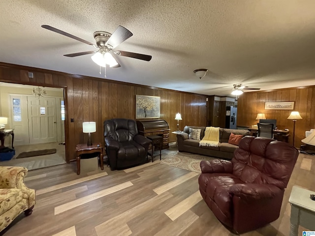 living room with ceiling fan, hardwood / wood-style flooring, a textured ceiling, and wood walls