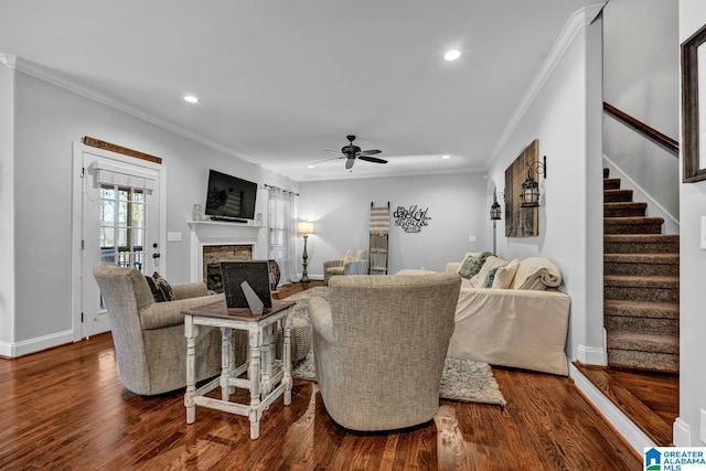 living room featuring hardwood / wood-style floors, a stone fireplace, ornamental molding, and ceiling fan