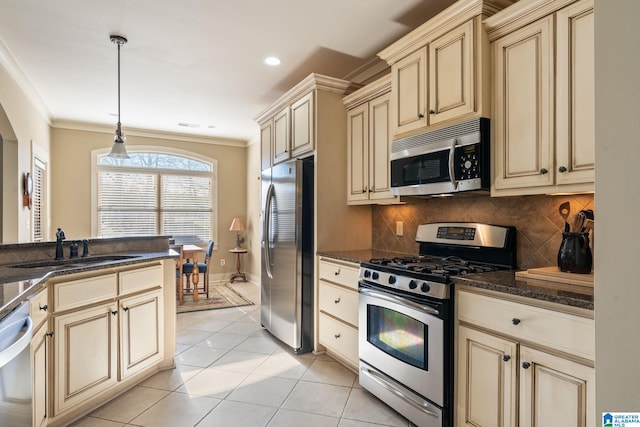 kitchen with sink, hanging light fixtures, ornamental molding, stainless steel appliances, and cream cabinetry