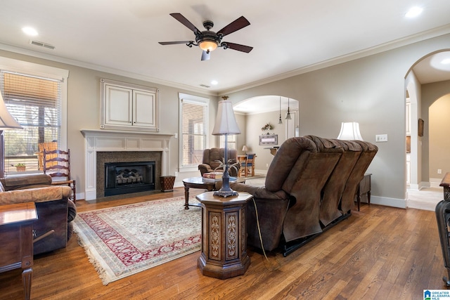 living room with wood-type flooring, ornamental molding, and ceiling fan