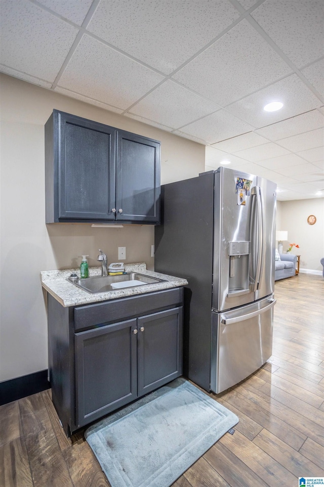 kitchen featuring stainless steel refrigerator with ice dispenser, sink, hardwood / wood-style floors, and a drop ceiling