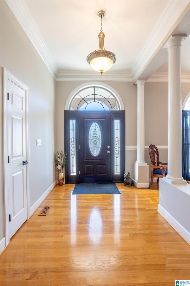 entryway with ornate columns, ornamental molding, and light hardwood / wood-style flooring