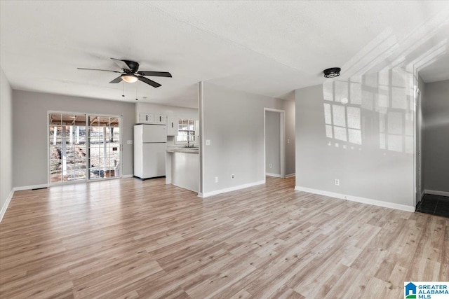 unfurnished living room featuring ceiling fan, a textured ceiling, and light wood-type flooring