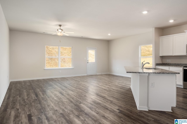 kitchen with stone counters, sink, white cabinets, and a center island with sink