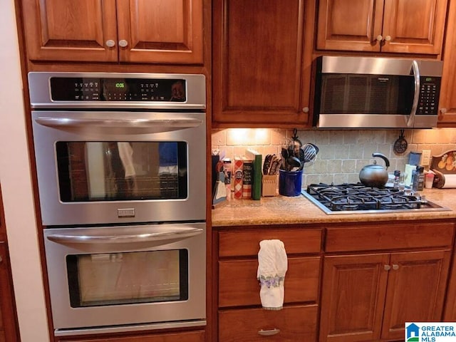 kitchen featuring light stone counters, appliances with stainless steel finishes, and decorative backsplash