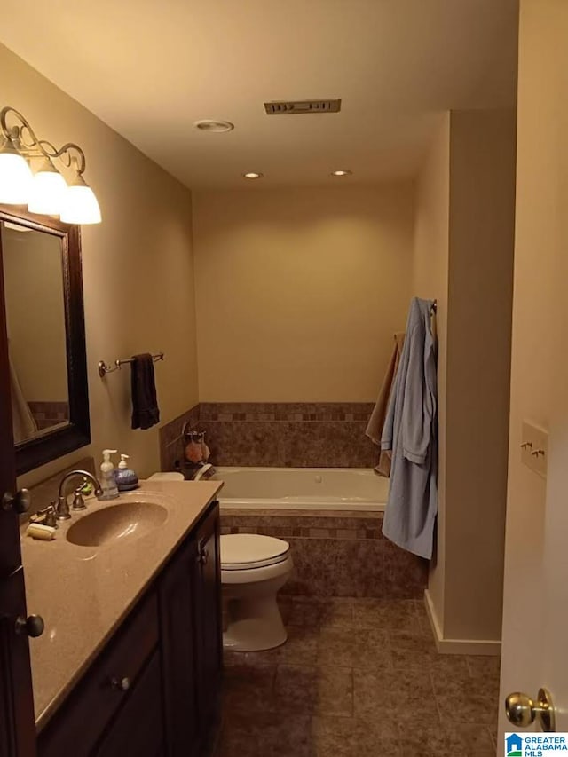 bathroom featuring vanity, tiled bath, and toilet