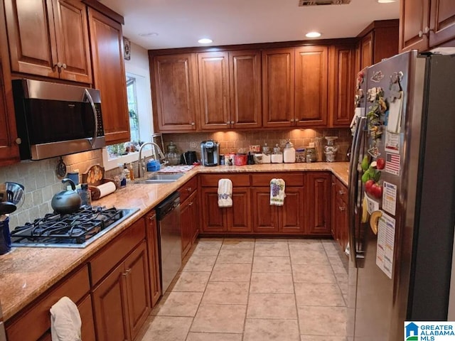 kitchen featuring light tile patterned floors, sink, appliances with stainless steel finishes, backsplash, and light stone counters