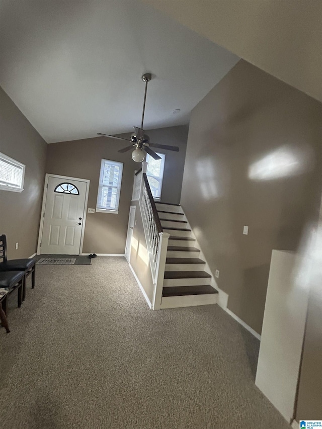 entrance foyer with lofted ceiling, ceiling fan, and carpet flooring