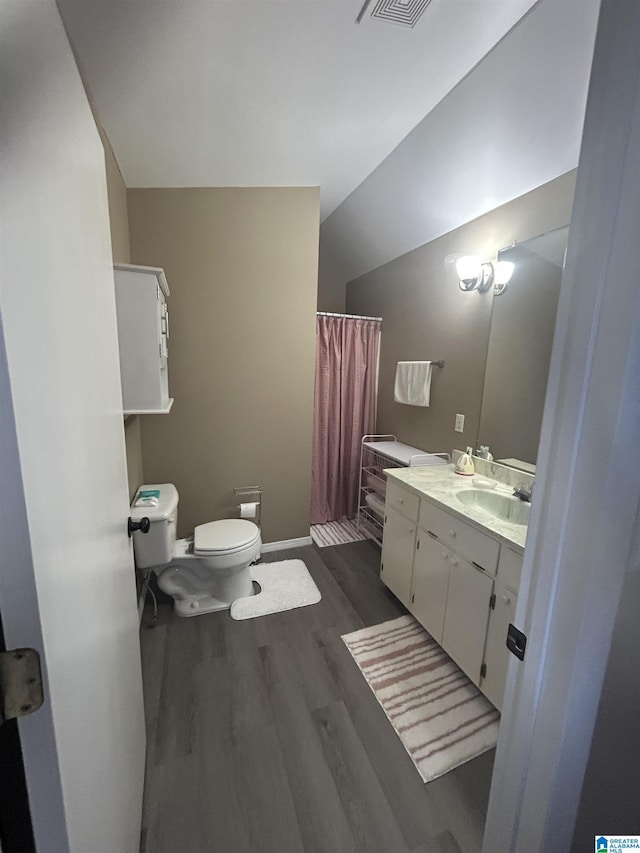 bathroom featuring lofted ceiling, hardwood / wood-style floors, vanity, toilet, and walk in shower