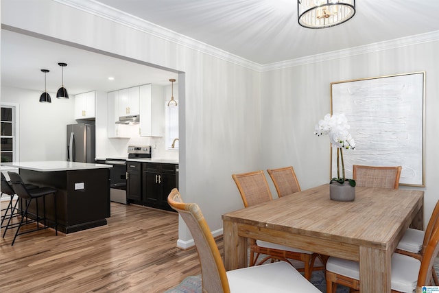 dining area featuring crown molding, light hardwood / wood-style flooring, and a notable chandelier