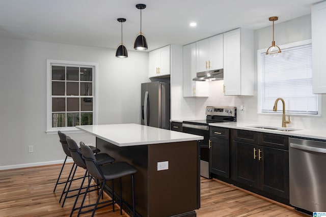 kitchen with a kitchen bar, a kitchen island, white cabinets, and appliances with stainless steel finishes