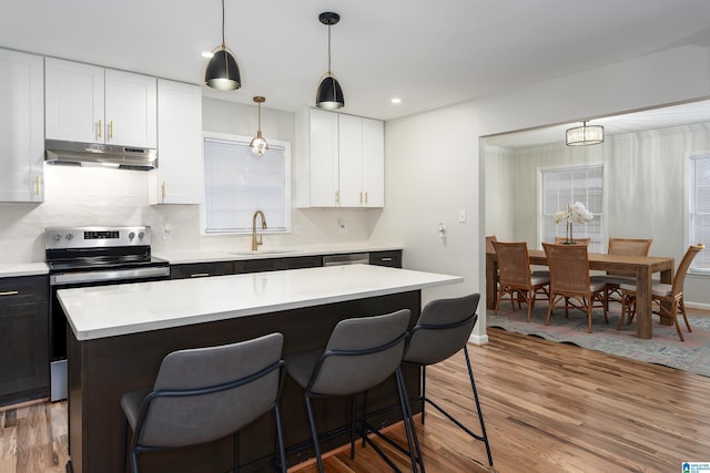 kitchen featuring a kitchen island, white cabinetry, wood-type flooring, sink, and hanging light fixtures