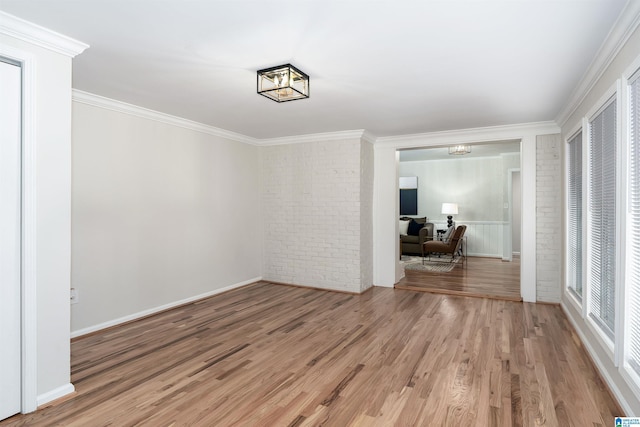 interior space with wood-type flooring, ornamental molding, and brick wall