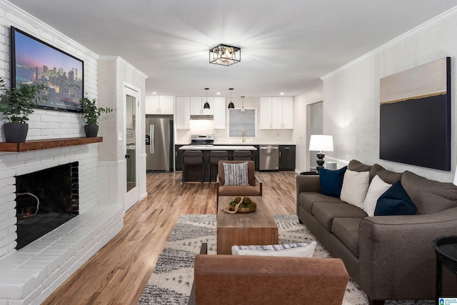 living room featuring ornamental molding, a fireplace, and light hardwood / wood-style flooring