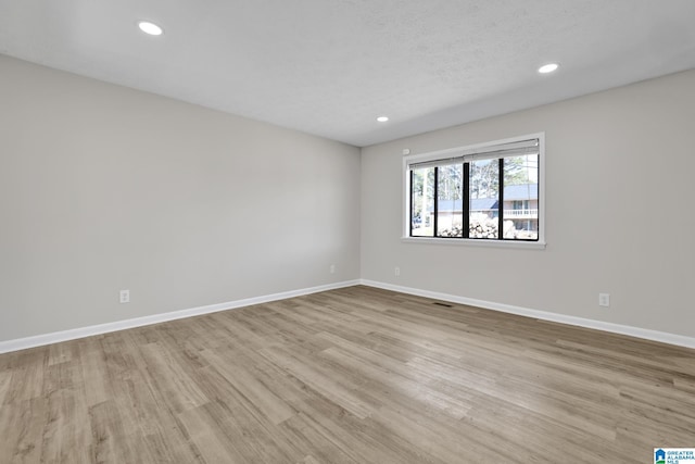 unfurnished room with a textured ceiling, baseboards, wood finished floors, and recessed lighting